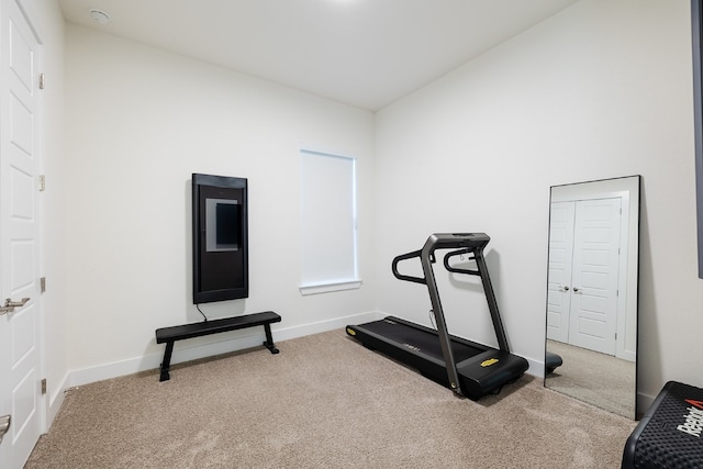 exercise room featuring vaulted ceiling and carpet flooring