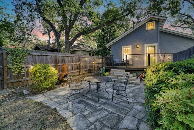 patio terrace at dusk featuring a wooden deck