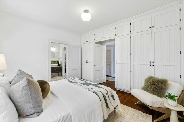 bedroom featuring ornamental molding, connected bathroom, and dark wood-type flooring