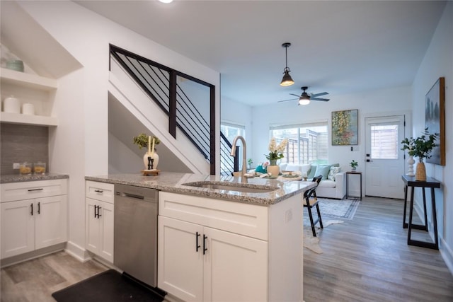 kitchen featuring sink, white cabinetry, light stone counters, decorative light fixtures, and dishwasher