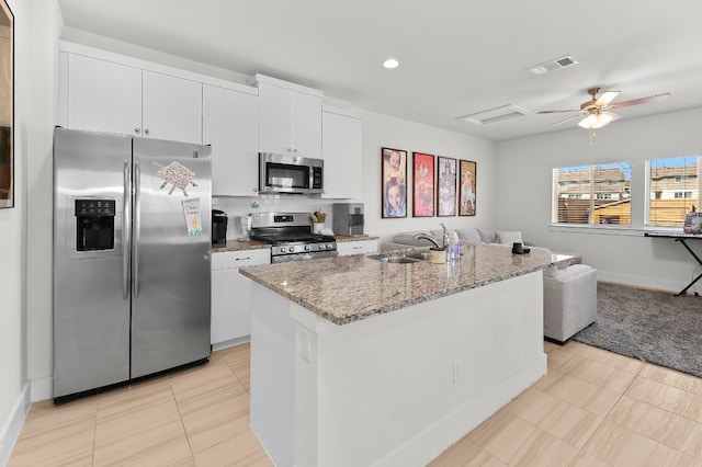 kitchen featuring a kitchen island with sink, sink, white cabinetry, stainless steel appliances, and backsplash