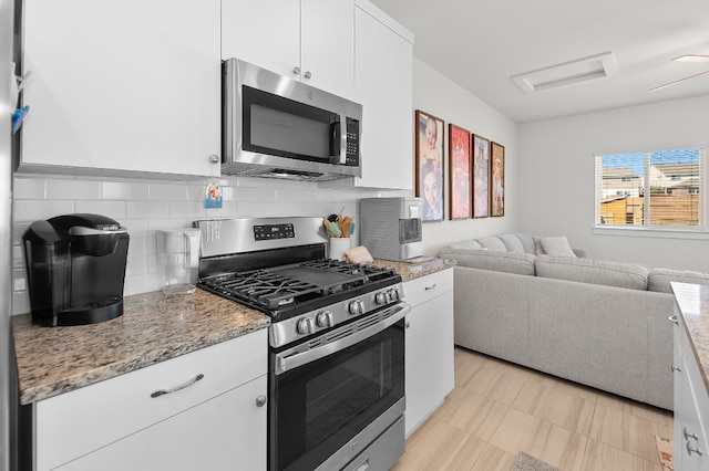 kitchen with white cabinetry, appliances with stainless steel finishes, stone counters, and backsplash