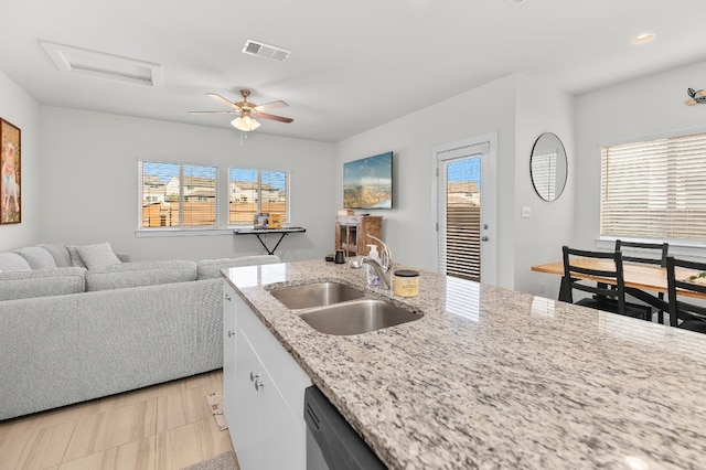 kitchen with light stone counters, white cabinets, ceiling fan, light tile patterned floors, and sink