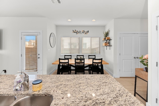 kitchen featuring light hardwood / wood-style flooring, light stone countertops, and sink