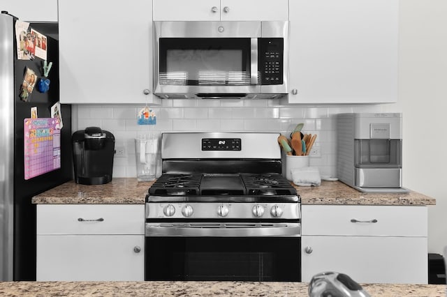 kitchen featuring light stone counters, white cabinets, appliances with stainless steel finishes, and decorative backsplash