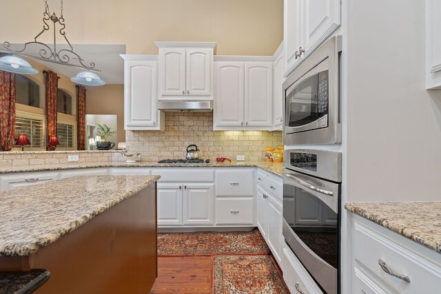 kitchen with backsplash, white cabinetry, stainless steel appliances, and decorative light fixtures