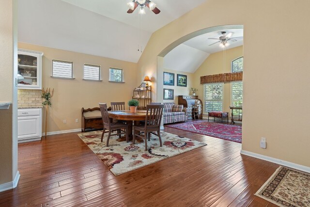 dining space featuring dark hardwood / wood-style flooring, ceiling fan, and high vaulted ceiling