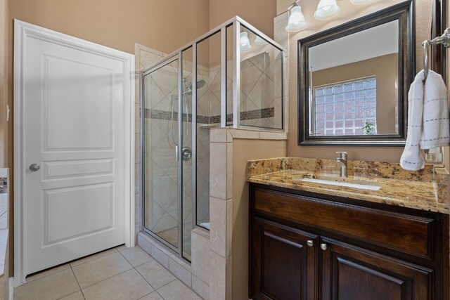 bathroom with walk in shower, vanity, and tile patterned flooring