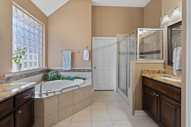 bathroom with plus walk in shower, lofted ceiling, tile patterned flooring, and vanity