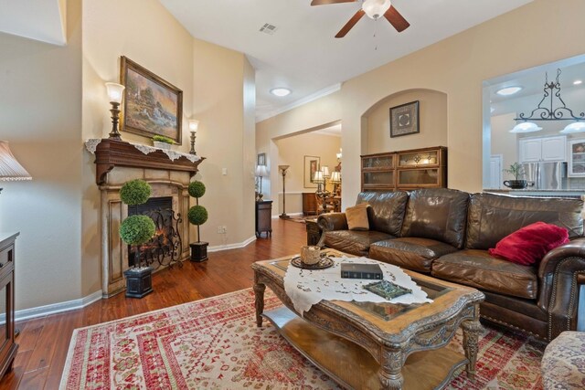 living room featuring ceiling fan, ornamental molding, and dark wood-type flooring