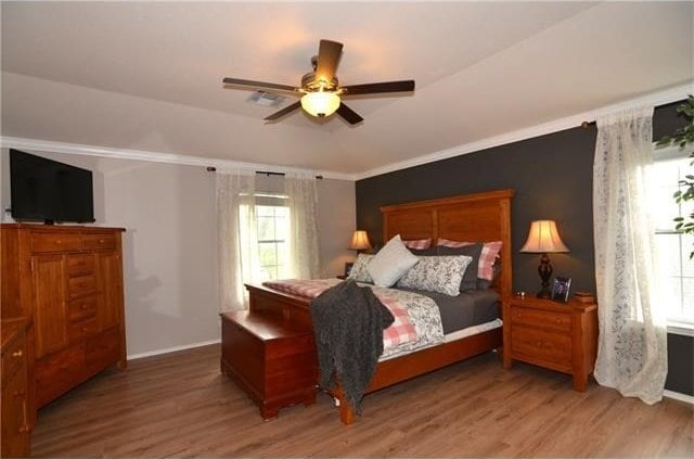 bedroom featuring wood-type flooring, ornamental molding, and ceiling fan