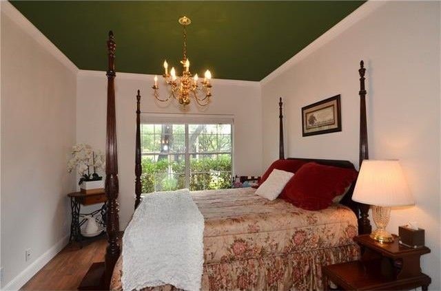 bedroom featuring a notable chandelier, hardwood / wood-style flooring, and crown molding