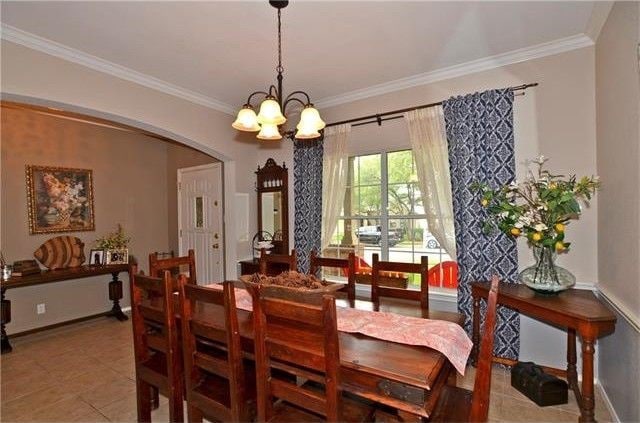 dining room featuring a notable chandelier, crown molding, and tile patterned floors