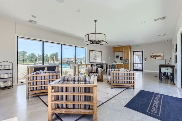 living room with visible vents, baseboards, concrete flooring, and an inviting chandelier