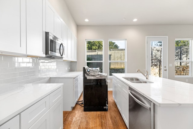 kitchen with white cabinets, a center island with sink, stainless steel appliances, and sink