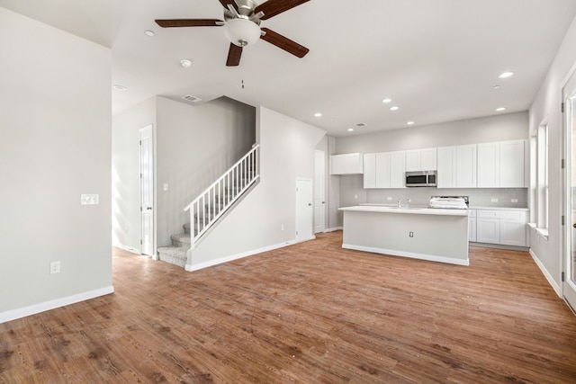 kitchen featuring light hardwood / wood-style floors, ceiling fan, a center island with sink, sink, and white cabinets