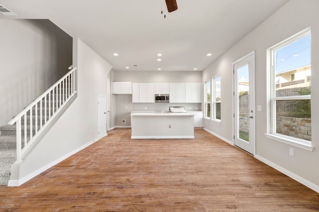 kitchen with plenty of natural light, a kitchen island with sink, white cabinetry, and light hardwood / wood-style floors