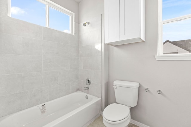 bathroom featuring a healthy amount of sunlight, toilet, and tiled shower / bath