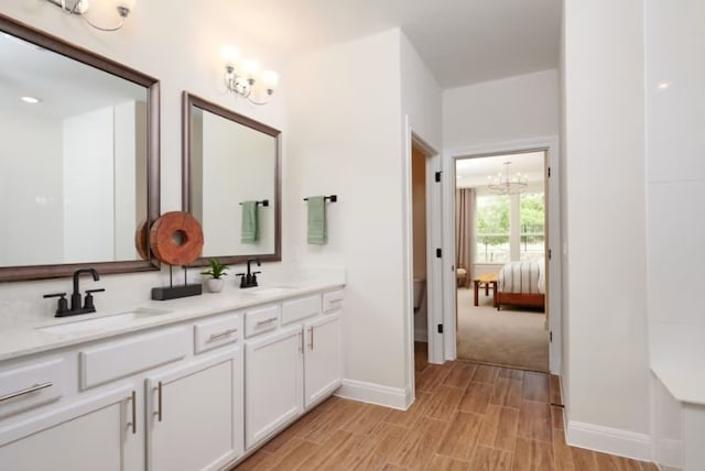 bathroom featuring wood-type flooring, an inviting chandelier, and vanity