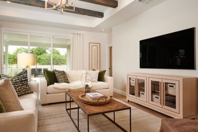 living room featuring beamed ceiling, an inviting chandelier, and light hardwood / wood-style flooring