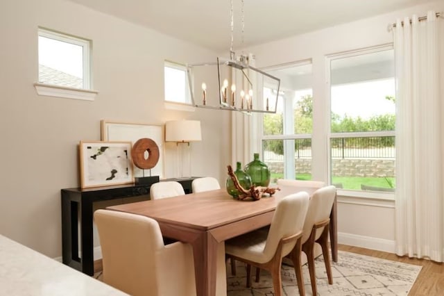 dining space featuring light wood-type flooring, an inviting chandelier, and a wealth of natural light