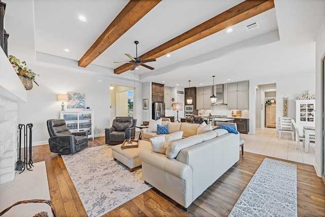 living room with ceiling fan, beam ceiling, and light hardwood / wood-style flooring