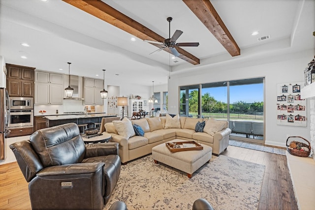 living room with ceiling fan, beam ceiling, and light hardwood / wood-style flooring