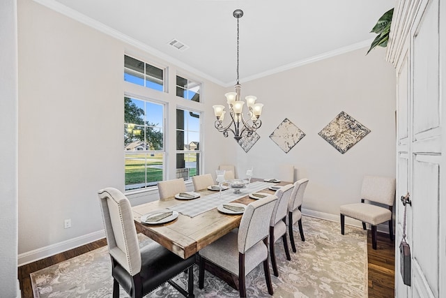 dining area with hardwood / wood-style flooring, an inviting chandelier, and crown molding