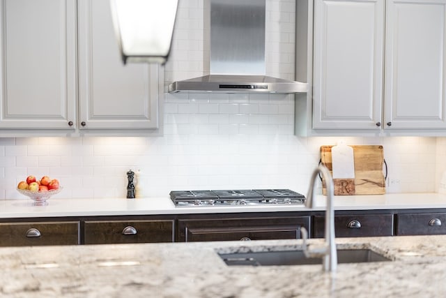 kitchen with white cabinets, decorative backsplash, and wall chimney exhaust hood