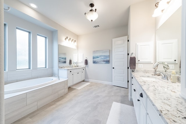 bathroom with tile patterned floors, tiled tub, and vanity