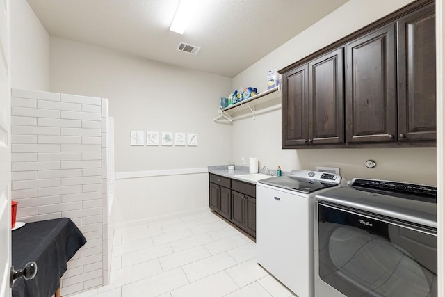 washroom with sink, cabinets, independent washer and dryer, a textured ceiling, and light tile patterned flooring