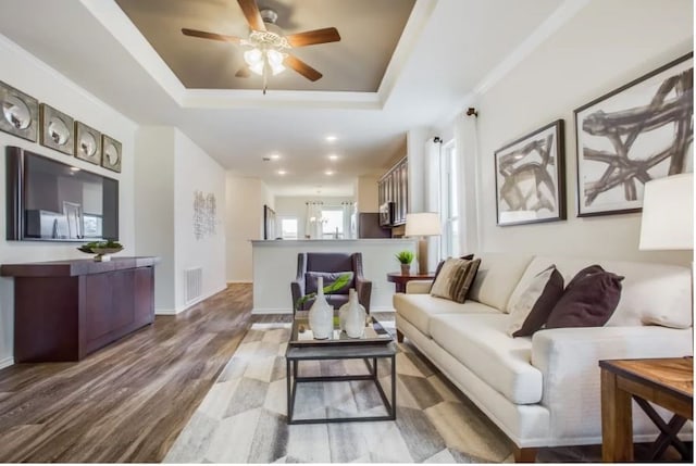 living room featuring ceiling fan, a tray ceiling, and light hardwood / wood-style floors