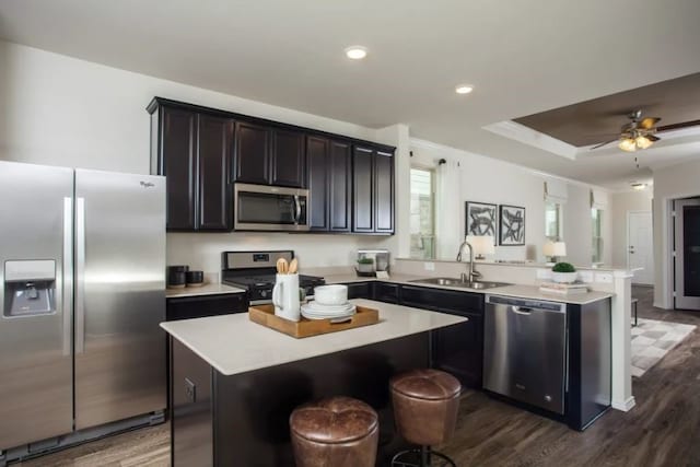 kitchen featuring a kitchen island, dark hardwood / wood-style floors, stainless steel appliances, a breakfast bar, and sink