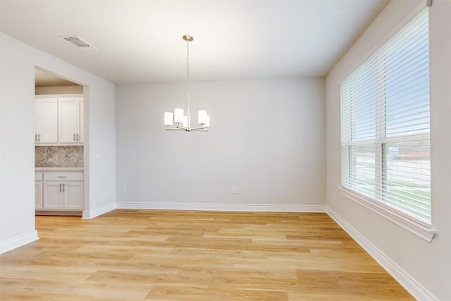 unfurnished dining area featuring light wood-type flooring and an inviting chandelier