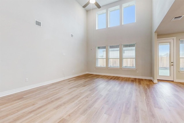 unfurnished living room with plenty of natural light, a high ceiling, and light hardwood / wood-style flooring