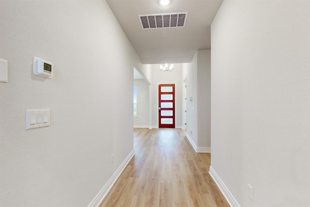 hallway with a chandelier and light hardwood / wood-style floors