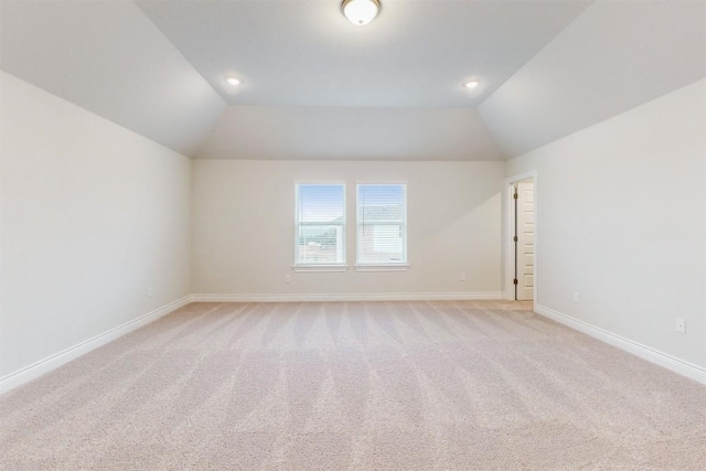 carpeted empty room featuring vaulted ceiling