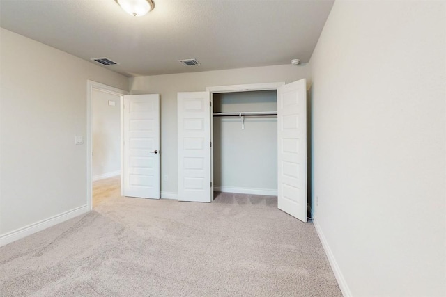 unfurnished bedroom featuring a closet and light colored carpet