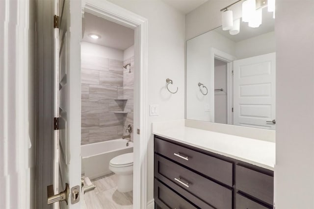 full bathroom featuring tiled shower / bath combo, toilet, and vanity