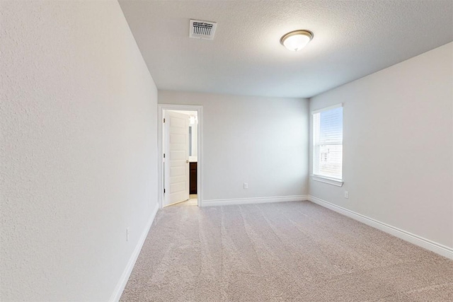 unfurnished room featuring a textured ceiling and light colored carpet