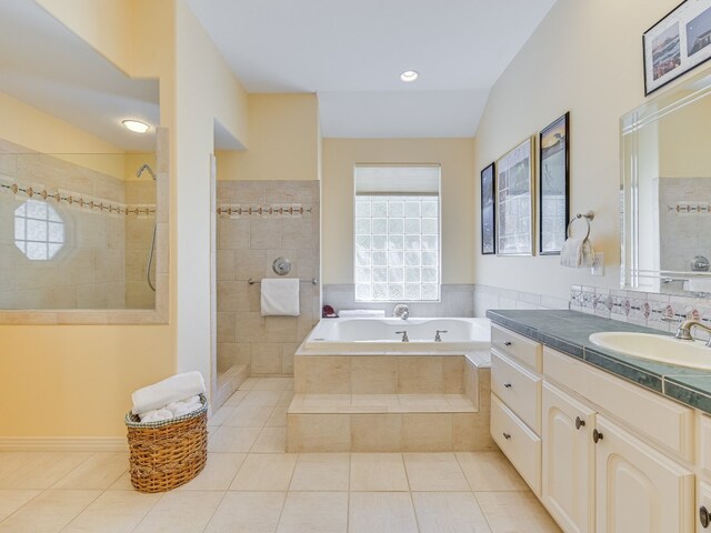 bathroom featuring independent shower and bath, vanity, lofted ceiling, and tile patterned floors