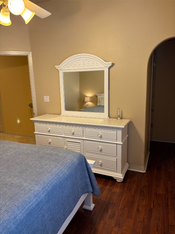 26801 Founders Pl, Spicewood, TX 78669 - bedroom with arched walkways, dark wood-style flooring, baseboards, and ceiling fan