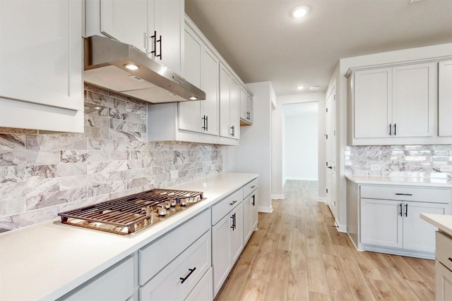 kitchen with backsplash, white cabinetry, light hardwood / wood-style floors, and stainless steel gas stovetop