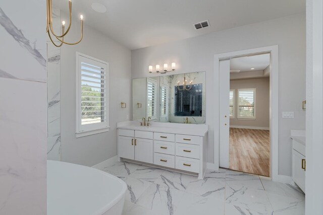 501 Francis Ct, Liberty Hill, TX 78642 - full bath featuring a chandelier, marble look tiles, vanity, a freestanding bath, and baseboards