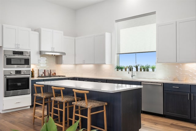 kitchen featuring white cabinets, appliances with stainless steel finishes, sink, and a center island