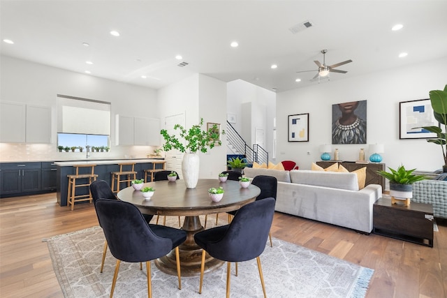 dining space featuring light wood-type flooring, ceiling fan, and sink