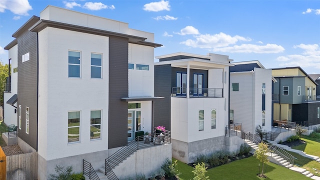 back of property with a yard and a balcony