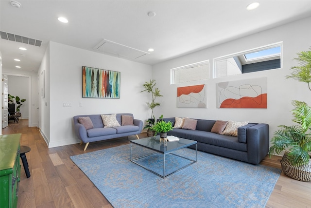 living room featuring wood-type flooring and a skylight