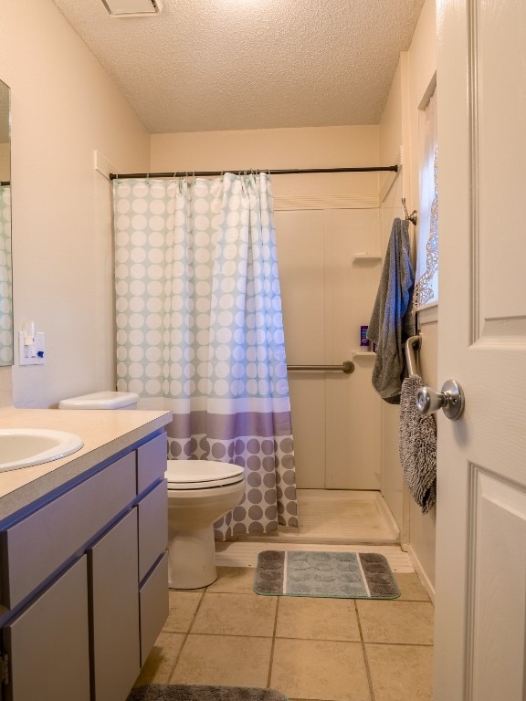 bathroom featuring toilet, a shower with curtain, tile patterned floors, vanity, and a textured ceiling