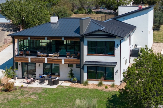 rear view of property with outdoor lounge area, a patio, and a lawn